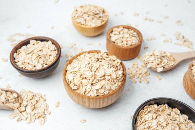 Yulaf dolu çeşitli kaseler yemek pişirmek için beyaz bir yüzey üzerinde sergilenir.