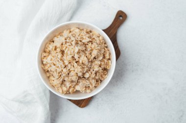 Kremalı yulaf ezmesi ahşap bir kesme tahtasının üzerinde bir kasede sunuluyor, eğlenmeye hazır..