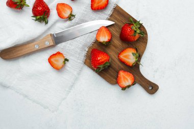 Taze çilekler evdeki tahta kesme tahtasıyla dilimleniyor..