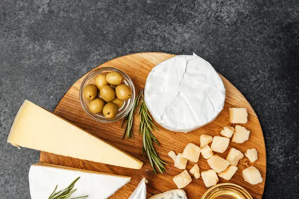 Peynir, zeytin ve otlardan oluşan tuzlu bir karışım tahtada güzelce sunuluyor..