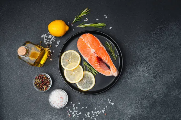 Limon dilimleri, otlar ve baharatlarla süslenmiş somon filetosu hazırlanmaya hazır..