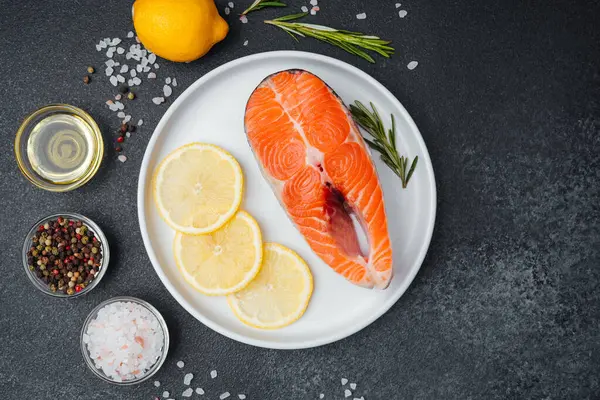Limon dilimleri, tuz ve çeşitli baharatlarla bir tabağa konmuş somon filetosu..