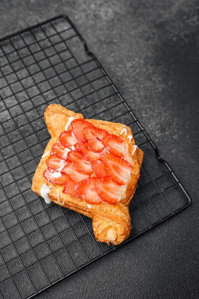 Altın hamurlu sıcak bir pasta dilimlenmiş taze çileklerle kaplıdır..