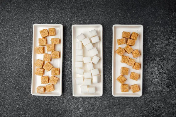 Değişik tipte şeker küpleri, arka planda üç tepsiye düzgünce yerleştirilir..