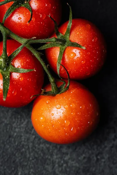 Siyah arka planda duran su damlacıkları olan parlak kırmızı domatesler..