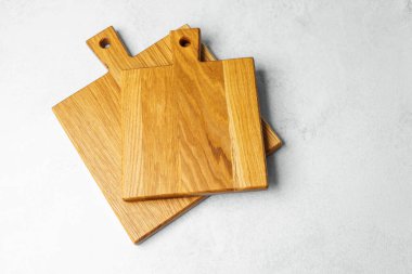 Üç tahta kesme tahtası, açık gri mutfak tezgahına güzelce yerleştirilmiş..