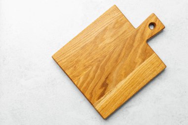 Şık bir ahşap kesme tahtası hafif bir yüzeye dayanır ve pürüzsüz sonunu vurgular..