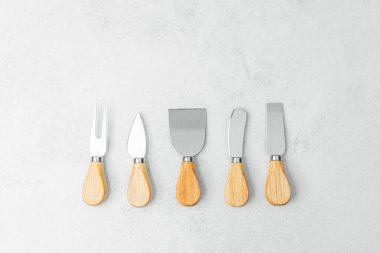 Tarafsız bir zemine dizilmiş tahta saplı beş farklı mutfak aleti..