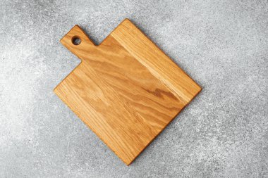 Gri bir yüzeye yerleştirilmiş tahta kesme tahtası doğal tahıl desenlerini sergiliyor..