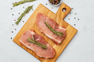 Biberiyeli ve biberiyeli domuz pirzolası dilimleme tahtasına yerleştirilmiş..