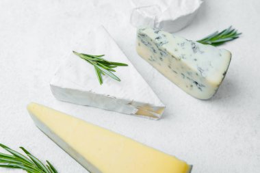 Ekranı güçlendiren otlarla güzelce düzenlenmiş üç farklı peynir türü..