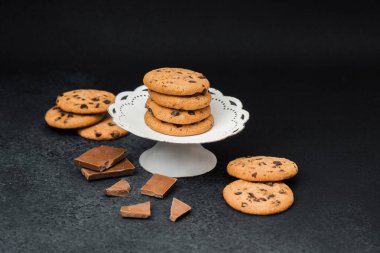 Çikolata parçalı kurabiyeler, yanında çikolata parçacıkları olan bir pasta standında düzenlenir..