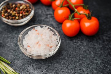 Koyu arkaplanda kiraz domatesli, biberiyeli pembe himalaya tuzu.