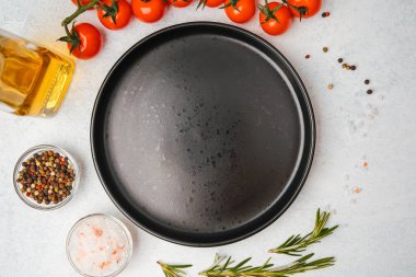 Domates, biberiye, tuz, yağ ve biber içeren yemek malzemelerinin olduğu boş siyah tabağın üst görüntüsü