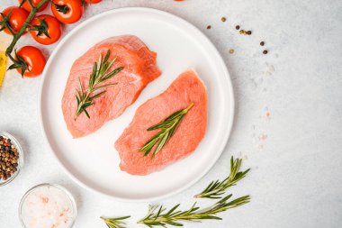 Baharat ve sebzelerle çevrili, beyaz tabakta biberiyeli iki dana biftek.