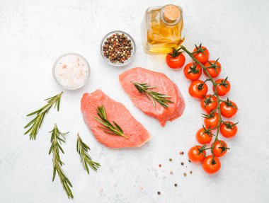 Beyaz arka planda baharatlı dana bifteği ve bitkilerin üst görüntüsü, yakın plan yağ ve biber dahil.