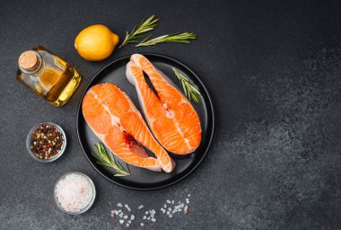 Somon filetoları bir tabakta otlar, limon ve zeytinyağının yanında pişmeye hazır bekliyor..