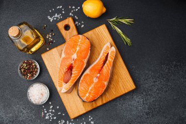 Baharat ve limonla ahşap bir tahtaya dizilmiş parlak somon filetoları..