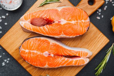 İki taze somon filetosu ahşap kesme tahtasının üzerinde canlı renkler sergiliyor..