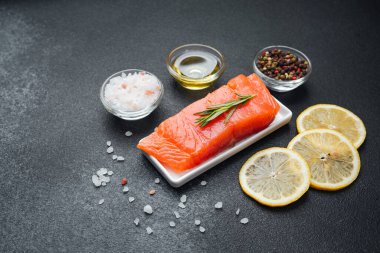 Bitkiler, tuz ve limon dilimleriyle süslenmiş somon filetosu pişirmeye hazır..