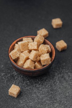 Kahverengi şeker küpleri ahşap bir kasede dağınık parçaların yanında düzgünce düzenlenir..