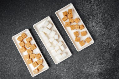 Tatlı sunumu için dikdörtgen tabaklarda kahverengi ve beyaz şeker küpleri sergilenir.