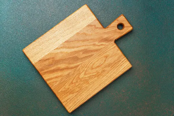Ahşap kesme tahtası, yemek hazırlamak için ideal, dokulu yeşil bir yüzeye yerleştirilir..