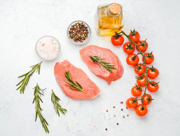 Beyaz arka planda baharatlı dana bifteği ve bitkilerin üst görüntüsü, yakın plan yağ ve biber dahil.