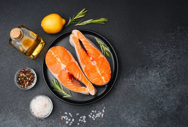 Somon filetoları bir tabakta otlar, limon ve zeytinyağının yanında pişmeye hazır bekliyor..