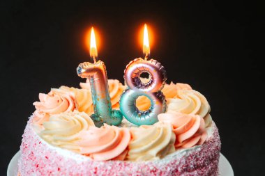 Göz kamaştırıcı bir doğum günü pastasında 18. yaş gününü kutlayan pembe şekerleme ve mumlar var..