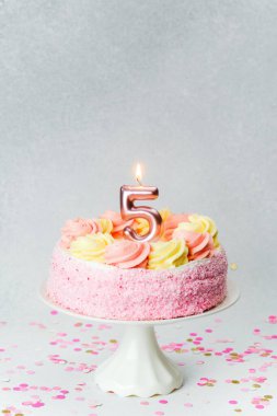 Buzlu pembe bir doğum günü pastası ve bir mum bir çocuğun beşinci doğum gününü kutlar..