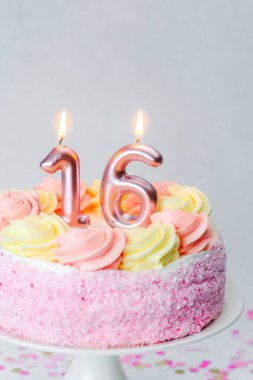 16. yaş günü için mumlar ve canlı süslemelerle süslenmiş pembe bir pasta..