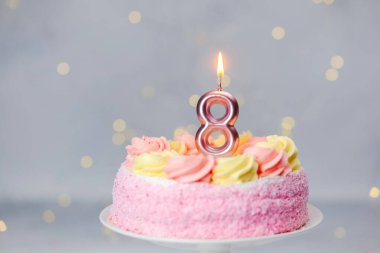 Güzel pembe bir doğum günü pastası, kremalı ve sekiz mum parıldıyor..