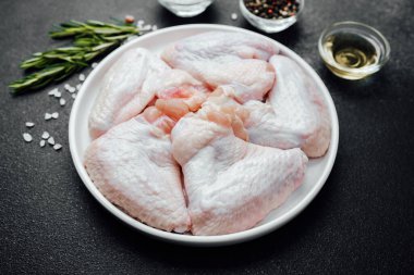 Baharatlı baharatlı tavuk kanatları ve koyu taşlı arka planda yağ.