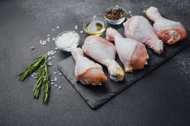 Siyah tahta üzerine yerleştirilmiş tavuk budu, otlar ve tuzlu.