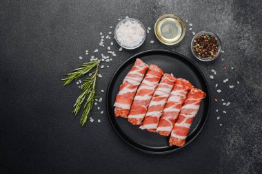 Domuz pastırmasına sarılı çiğ et ruloları ve baharatlar.