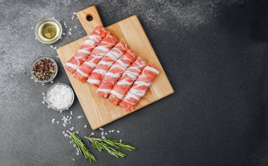 Pastırmaya sarılı çiğ et ruloları ahşap tahtaya baharatlı.