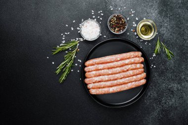 Siyah tabakta çiğ domuz sosisi ve biberiye.