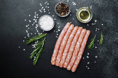 Siyah taş masada baharatlı çiğ sosisler.