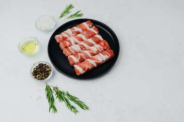 Domuz pastırması siyah tabakta baharat ve biberiye ile sarılmış.