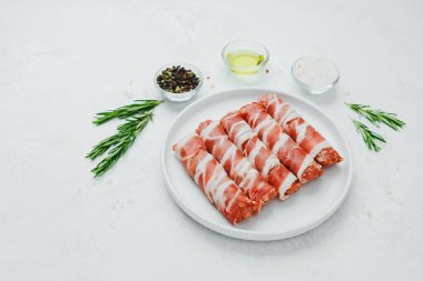 Jambona sarılmış sosis, beyaz tabakta otlar ve yağla birlikte.