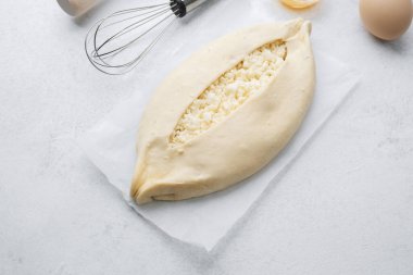 Beyaz zemin üzerinde yumurta sarısı ve peynirli çiğ khachapuri.