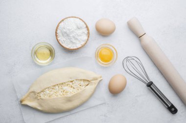 Parşömen üzerinde peynir ve fırın malzemeleri olan fırınlanmamış khachapuri.