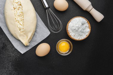 Parşömen üzerinde peynir ve sarısı olan Khachapuri ve koyu mutfak masası.