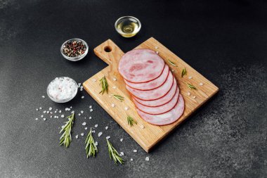 Siyah masa arkasında tuzlu ve biberiyeli dilimlenmiş domuz sosisi.