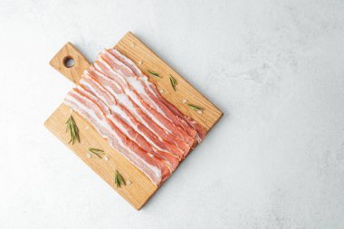 Ahşap tahtada çiğ pastırma dilimleri, biberiye ve koyu arkaplanda tuz.