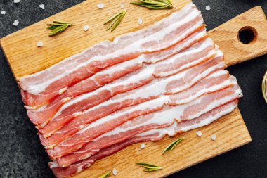 Siyah yüzeyde baharat ve biberiye ile sıralanmış jambon dilimleri.