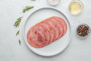 Beyaz tabakta dilimlenmiş sosis ve baharat.