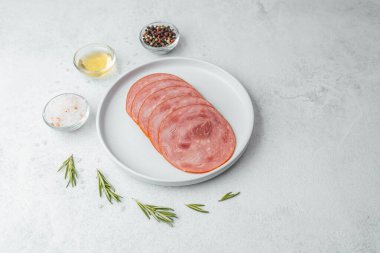 Beyaz tabakta dilimlenmiş sosis ve baharat.