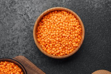 Parlak turuncu mercimekler el yapımı ahşap bir kâseyi doldurur..